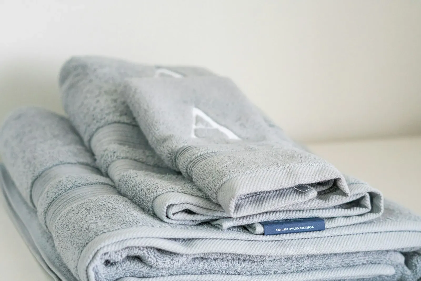 Stack of folded premium towels in soft neutral tones on a linen surface